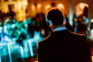 A wedding DJ mixing music at a wedding reception, surrounded by equipment and vibrant lighting, creating an energetic atmosphere.