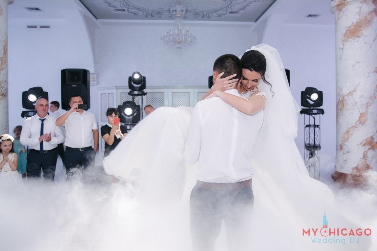 Bride and groom dancing with DJ in background