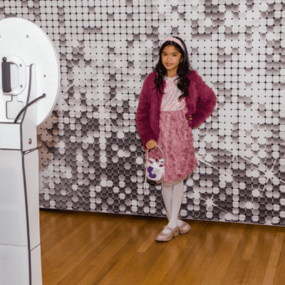 Flower girl posing at a wedding photo booth with a silver sequin backdrop at a Chicago wedding reception