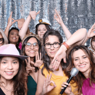 Wedding guests laughing and posing with props in a photo booth with a silver sequin backdrop at a Chicago wedding