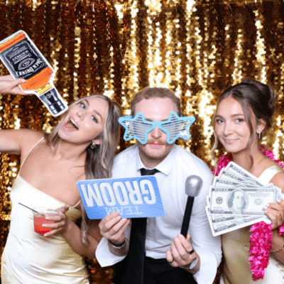 Wedding guests using a photo booth with props and a gold sequin backdrop at a Chicago wedding reception